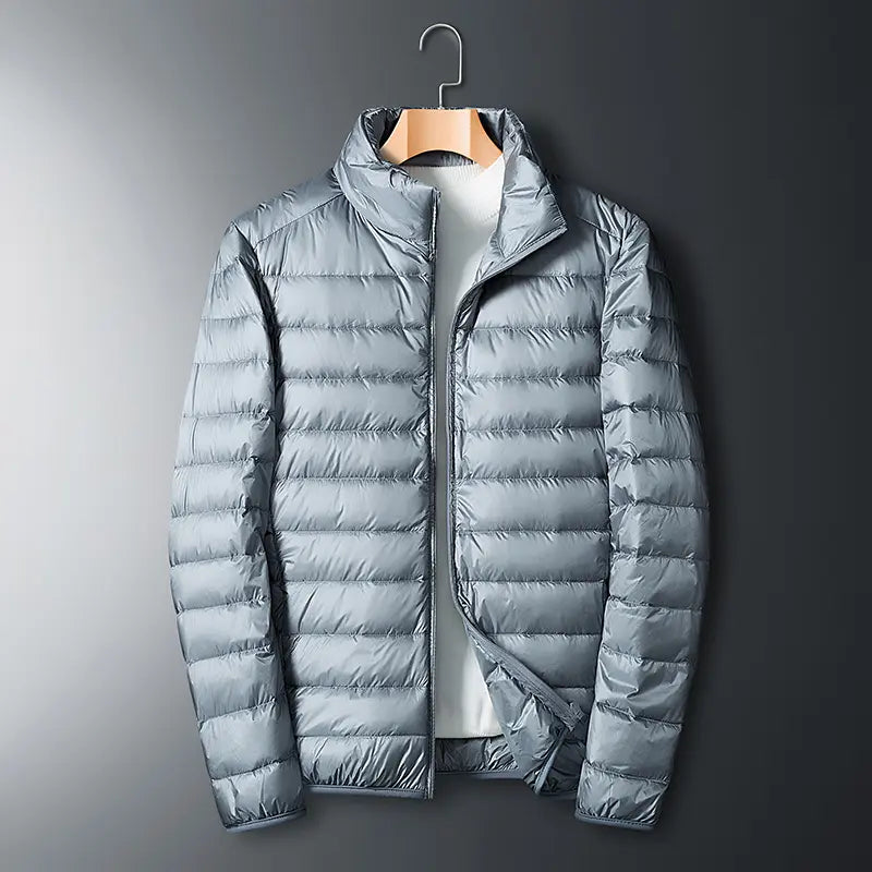 Men’s lightweight down jacket with a stand collar and storage feature; available in five colors; portable, compressible, warm, and highly puffy for autumn/winter; zippered outerwear; five-color stand-collar zippered portable travel outerwear for a...